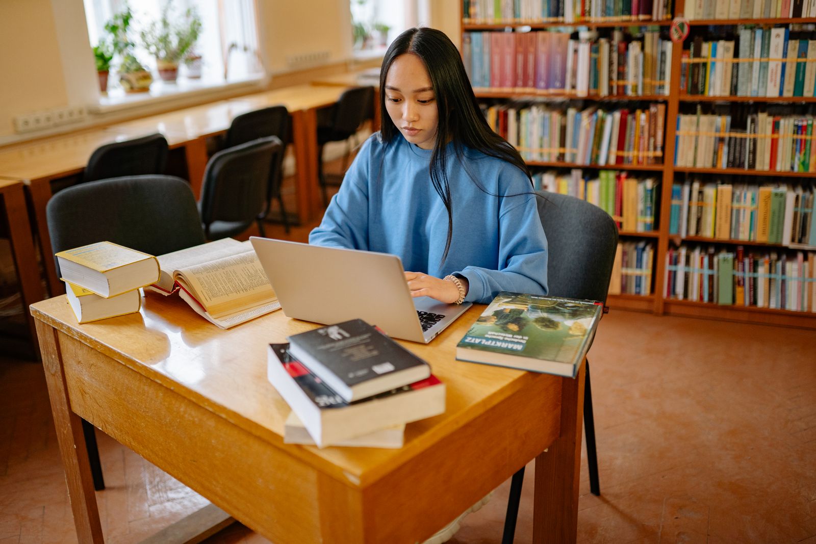 Student researching with a laptop and books in a library